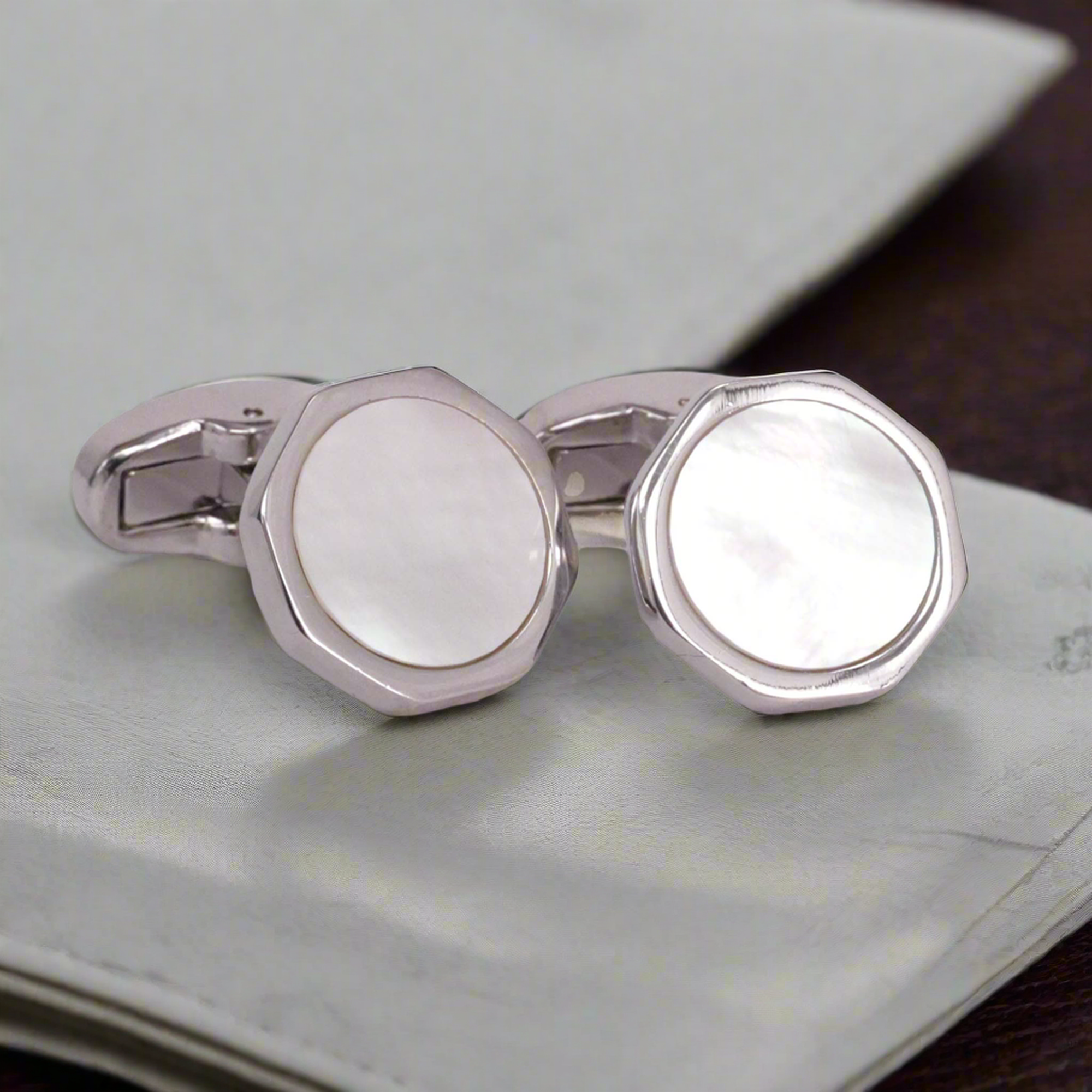A pair of rhodium-plated white mother-of-pearl hexagon cufflinks on a cuff.
