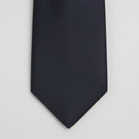 A close-up of a solid black necktie tip against a plain white background.