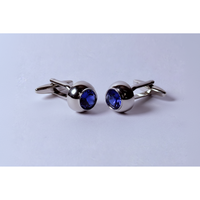 Pair of silver cufflinks with blue gemstones on a light gray background