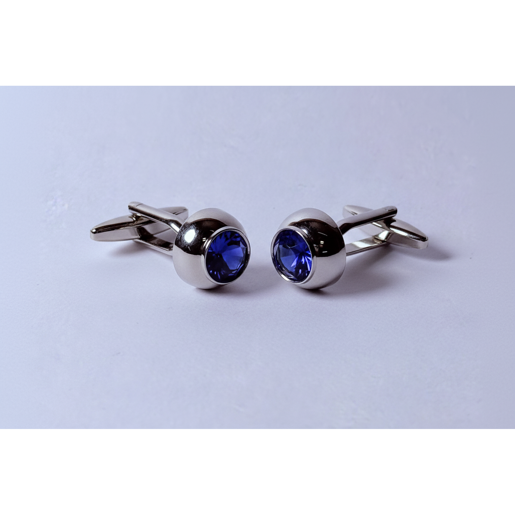 Pair of silver cufflinks with blue gemstones on a light gray background