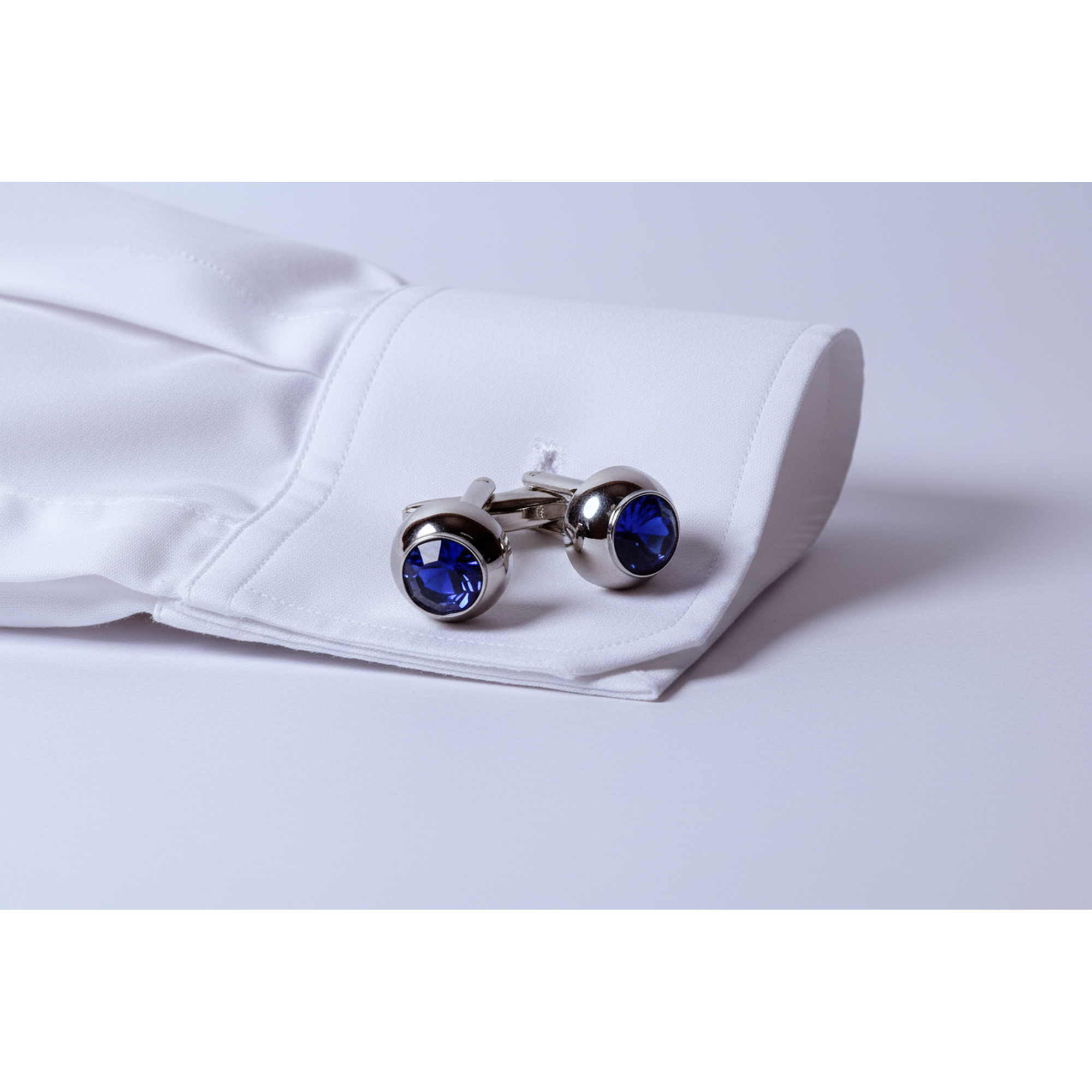 Pair of silver cufflinks with blue gemstones on a light gray background