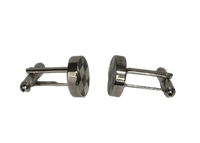 A pair of silver-toned metal cufflinks with oval faces, one showing a dark and light checkered pattern and the other showing a smooth polished finish, set against a plain light gray background.