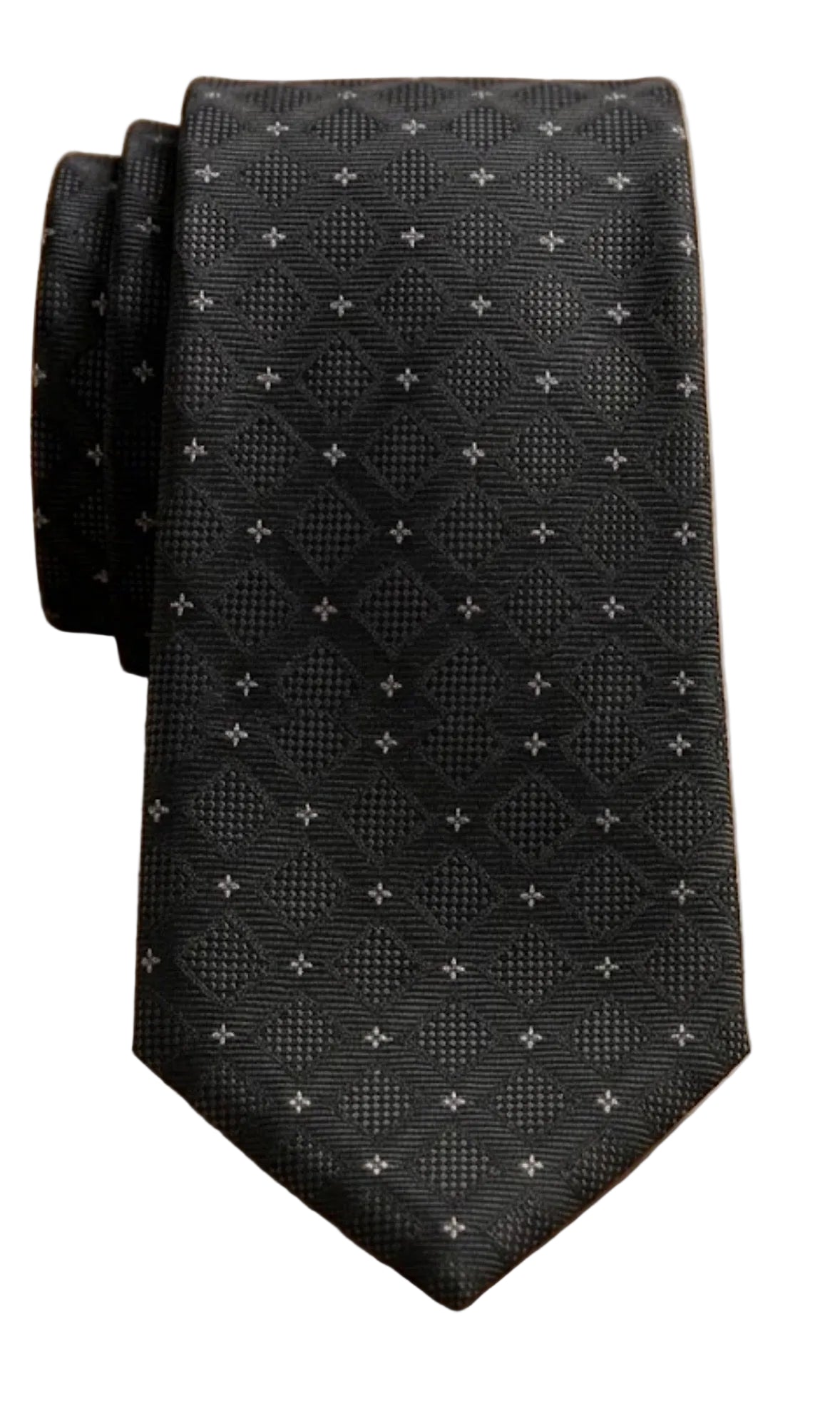 A black textured necktie with a small white geometric pattern, folded on a light wood grain surface.