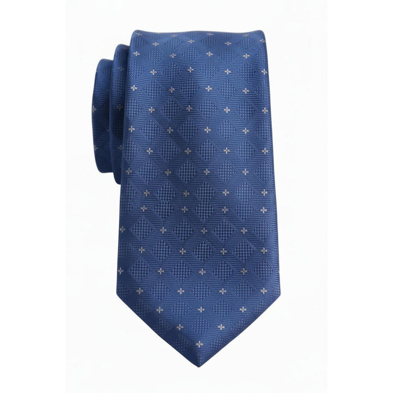 A blue necktie with a textured geometric diamond pattern and small white cross motifs, displayed on a light wood surface.