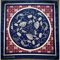 A square silk scarf featuring a classic botanical pattern with a navy blue center, a red border, and cream accents. The brand name 'A.