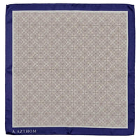 A square silk pocket square by A. Azthom, featuring a beige and brown geometric damask pattern in the center, a solid navy blue border, and the brand name printed in white at the bottom left corner.