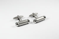 Silver cylindrical cufflinks on a white background